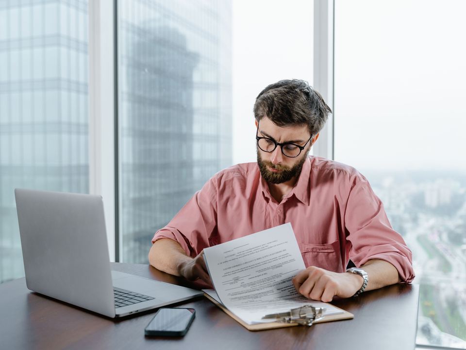 Un homme lit un document devant son ordinateur