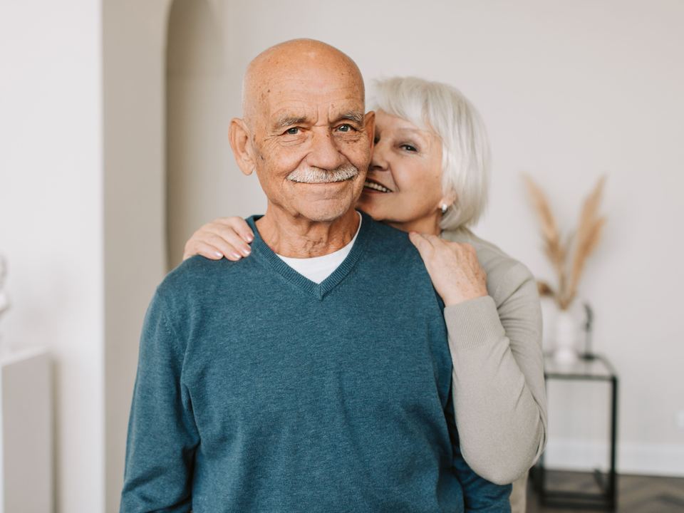 Un couple de retraités souriant, chez eux