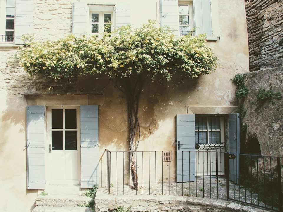 La façade en pierre d'une maison ancienne aux volets clairs
